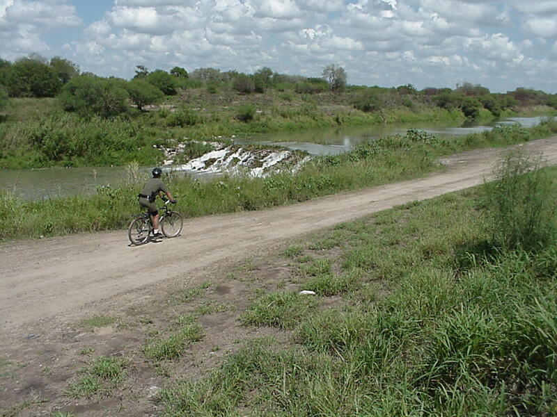 Border Patrol USBP miscellaneous modern bike patrol agent riding near a stream