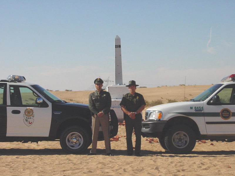 Border Patrol USBP miscellaneous modern agent and Mexican officer with a border monument