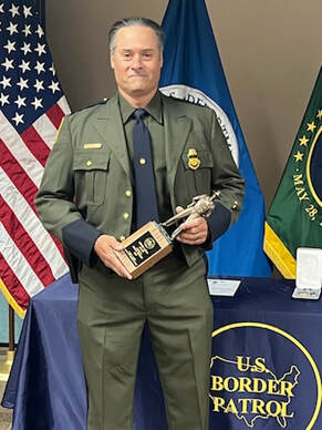 Border Patrol Agent Travis Creteau holding the Newton-Azrak Award statuette.