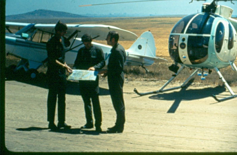 USBP Border Patrol photographs 1970-1990 agents standing next to an airplane and a helicopter