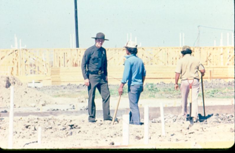 USBP Border Patrol photographs 1970-1990 an agent in dress uniform checking construction workers