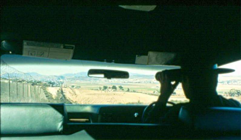 USBP Border Patrol photographs 1970-1990 an agent using binoculars while in a car
