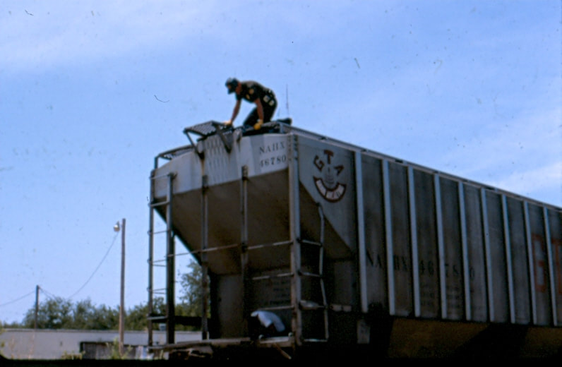 USBP Border Patrol photographs 1970-1990 agent looking over the side of a grain hopper train car