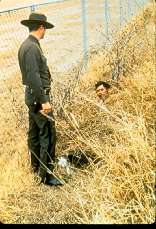 USBP Border Patrol photographs 1970-1990 alien hiding from an agent that is wearing a dress uniform