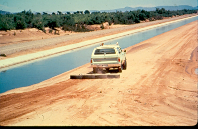 USBP Border Patrol photographs 1970-1990 sea foam green vehicle pulling tires near a canal