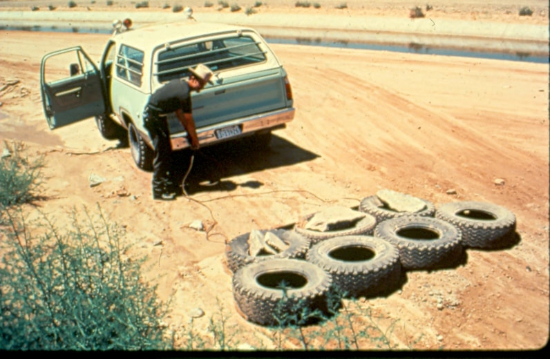 USBP Border Patrol photographs 1970-1990 agent connecting a tire drag to the back of a sea foam green suv
