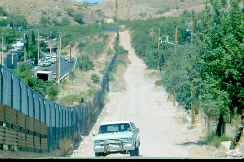 USBP Border Patrol photographs 1970-1990 sea foam green vehicle driving near the border fence