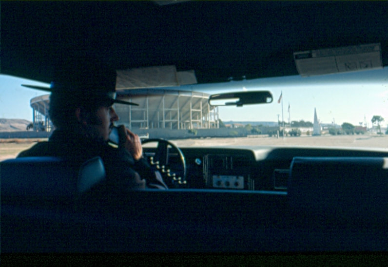 USBP Border Patrol photographs 1970-1990 agent wearing a dress uniform in a car speaking on a radio