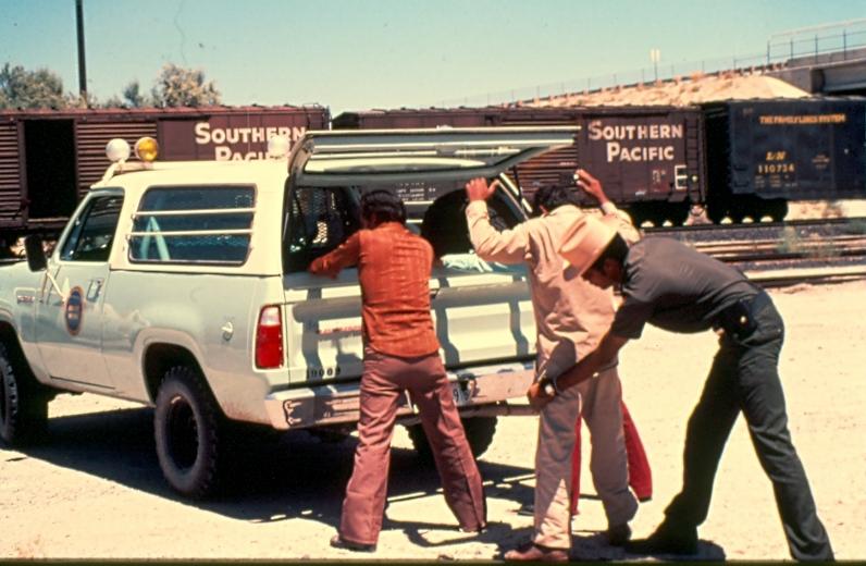 USBP Border Patrol photographs 1970-1990 agent searching arrestees behind a sea foam green SUV