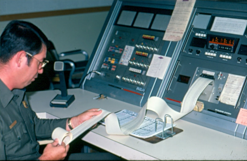 USBP Border Patrol photographs 1970-1990 agent looking at paperwork at a dispatch desk 