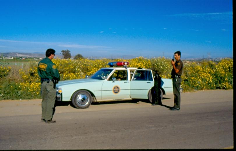USBP Border Patrol photographs 1970-1990 agents talking near a sea foam green car