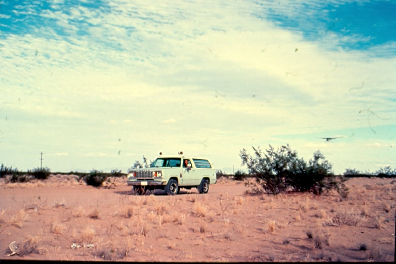 USBP Border Patrol photographs 1970-1990  sea foam green SUV with a airplane approaching