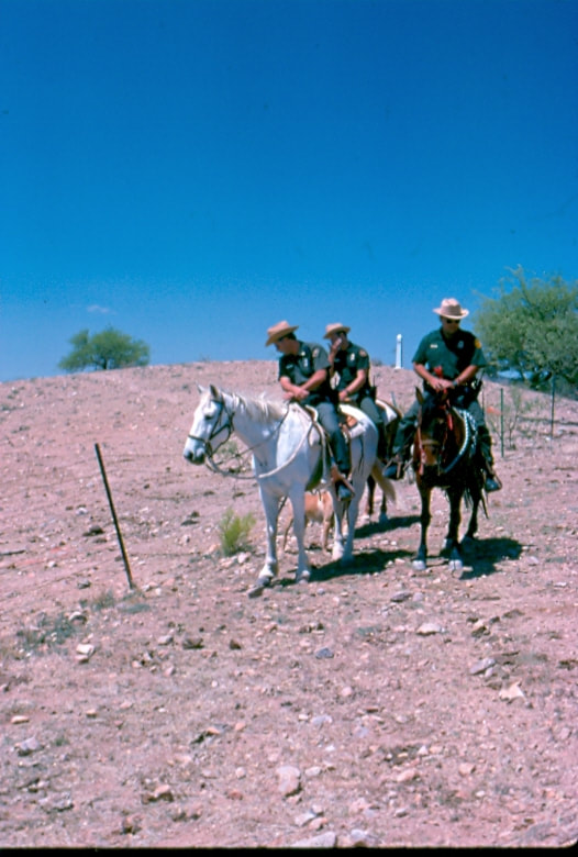 USBP Border Patrol photographs 1970-1990  three horse patrol agents riding in the desert along a fence